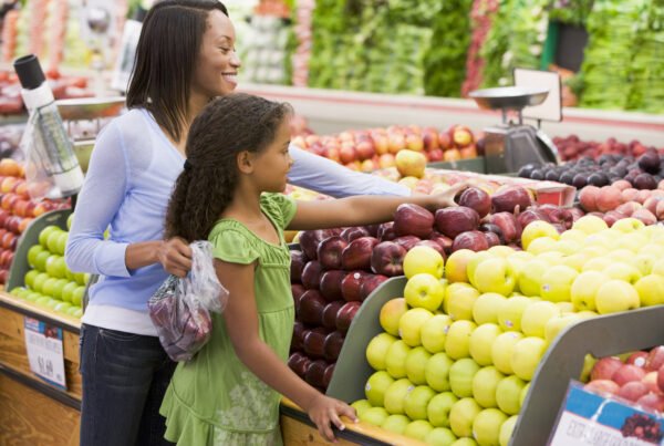 Mother and daughter in grocery store produce section.